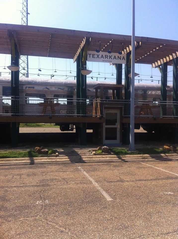 Train car restaurant in Texarkana, TX, with outdoor wooden pergola over a deck.