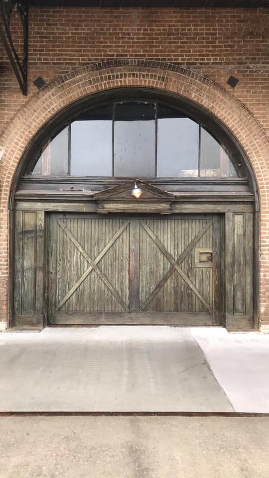 Large wooden arched doors with a half-moon window above, set in a brick building.