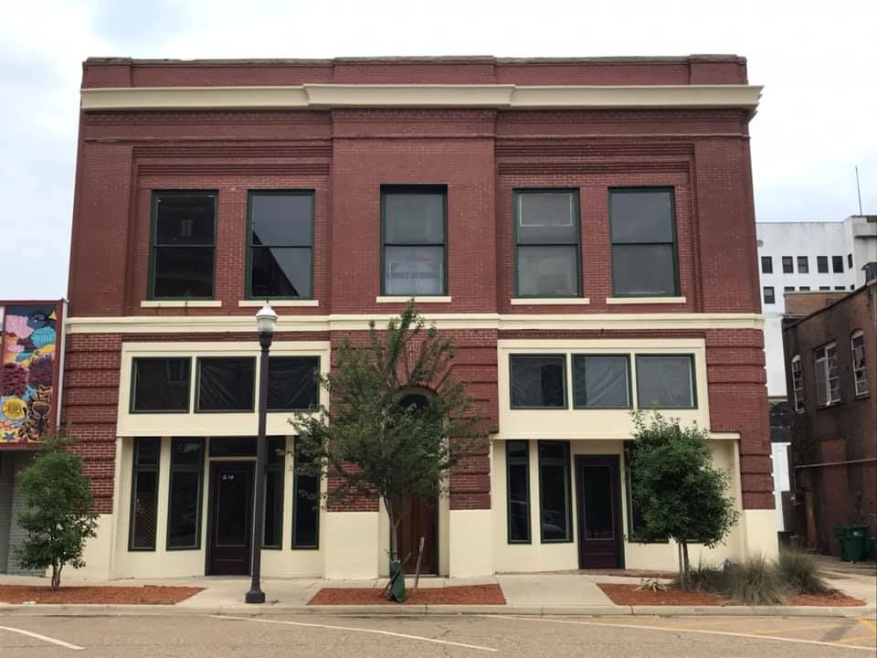 Two-story brick building with large windows and a tan trim.