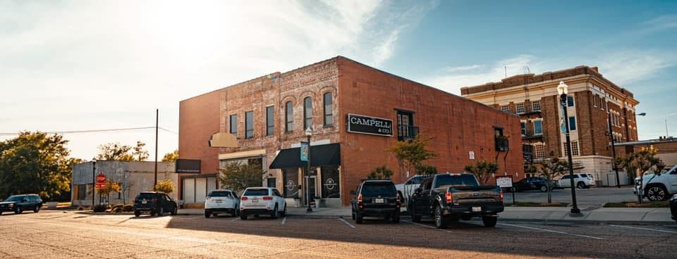 Buildings with cars parked out front on a sunny day.