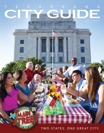 Texarkana City Guide cover: People at a picnic table with food and drinks in front of a building with an American flag.