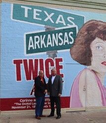 Two men stand in front of a mural with 