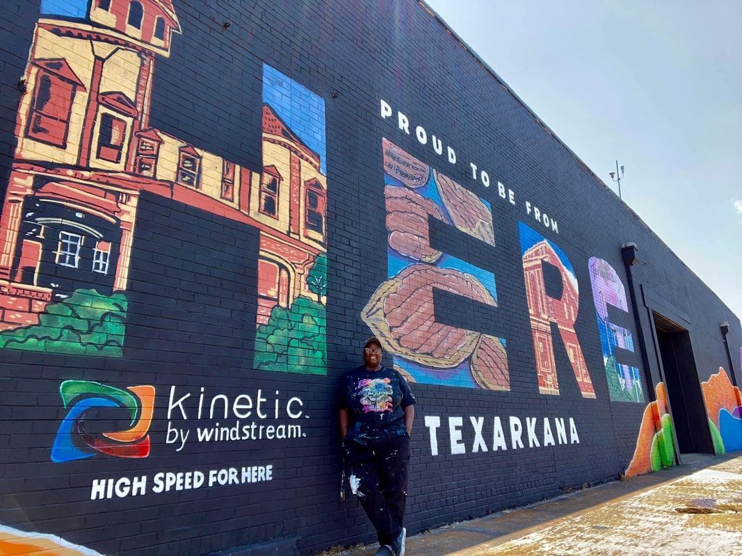 Person standing by a Texarkana mural on a black wall with the Kinetic logo.