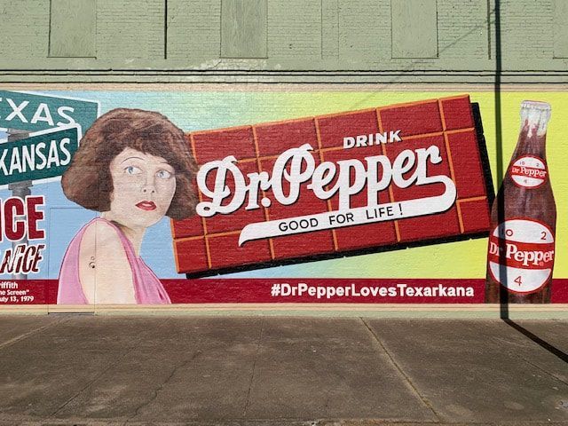 Mural of vintage Dr. Pepper ad in Texarkana; woman, bottle, and a red and white sign.