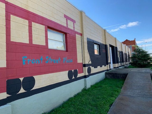 Mural of a red train car on a tan brick building; blue text reads