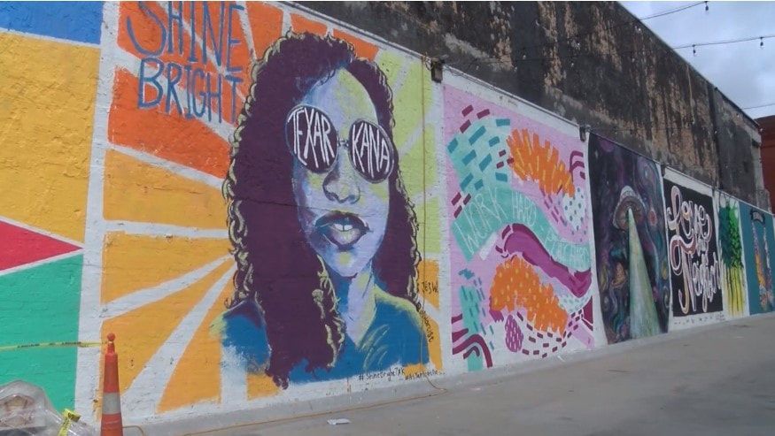 Colorful murals on a brick wall: portrait with sunglasses, abstract patterns, and