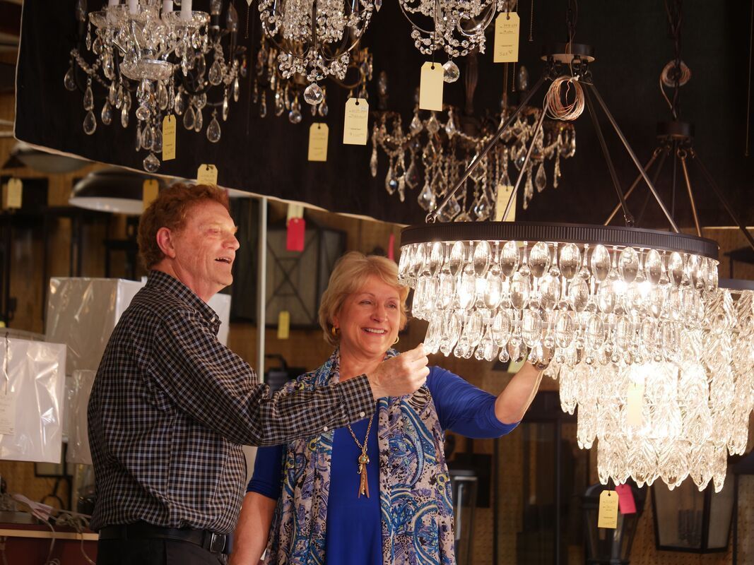 Couple admiring a crystal chandelier in a shop, both smiling.