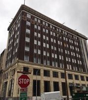 Brown brick building with many windows, stop sign in foreground.