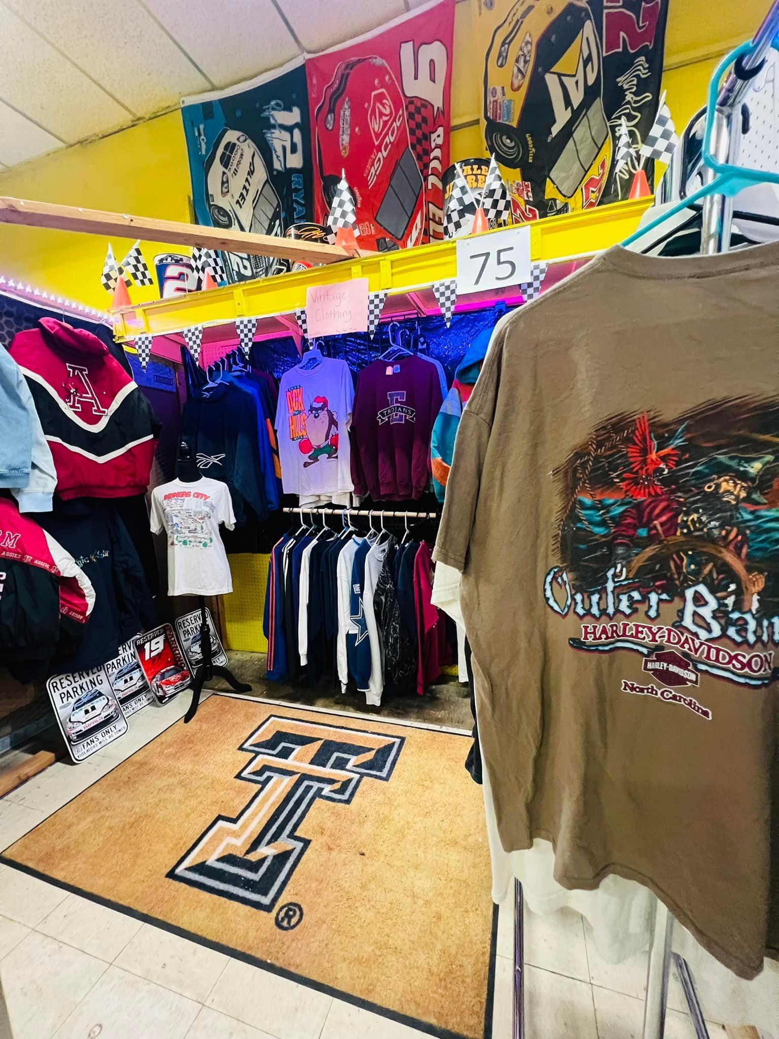 Vintage clothing store display with t-shirts, jackets, and banners. A Texas Tech rug is on the floor.