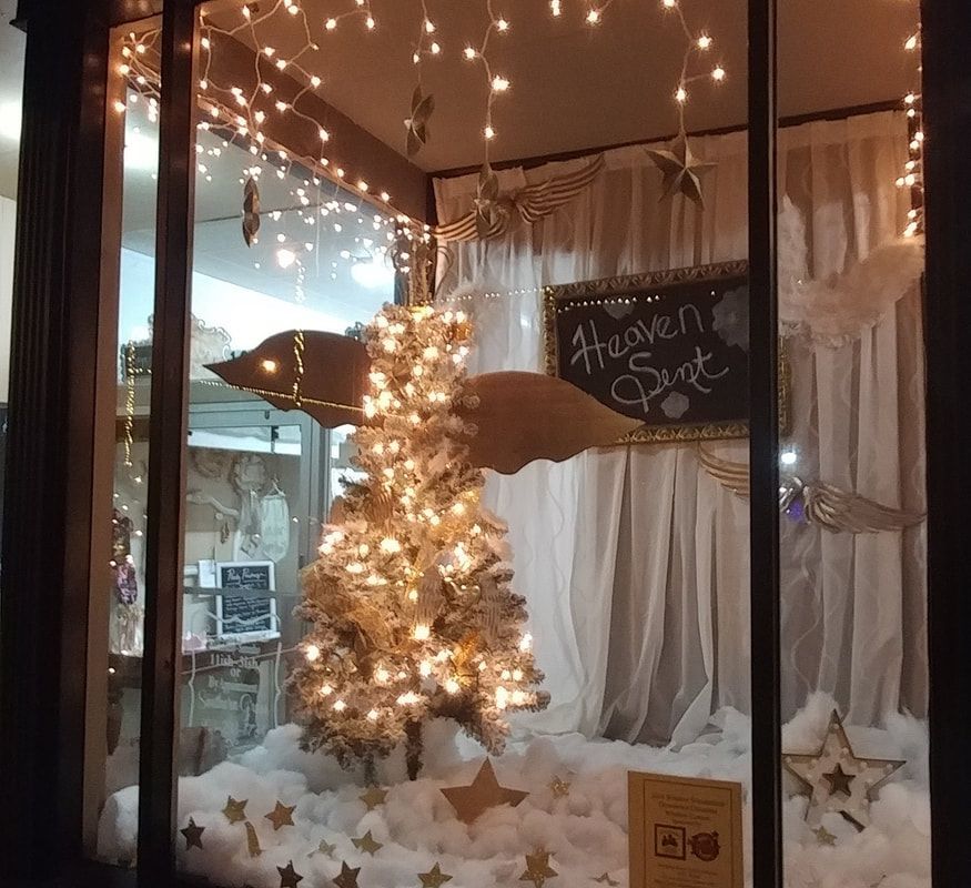 Christmas window display with tree, lights, angel wings, stars, and