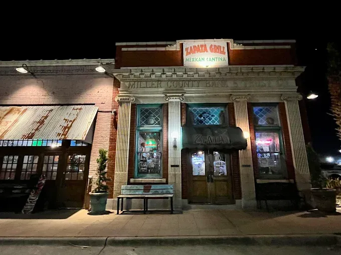 Night view of Sabata Grill Mexican Cantina with lit facade, brickwork, and arched windows.