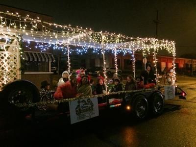 Christmas parade float with people under lights at night.