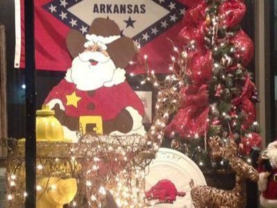 Christmas display with Santa, Arkansas flag, and decorated tree.
