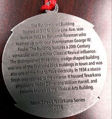 Silver medallion with text about the Rialto-Harrell Building in Texarkana; includes date, and building details.
