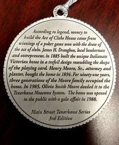 Silver medallion with text about the Ace of Clubs House in Texarkana, detailing its history and ownership.