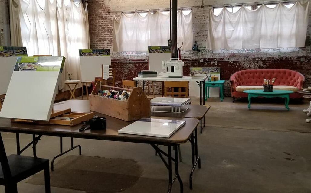 An art studio with easels, tables, a sofa, and exposed brick walls.
