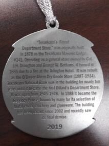 Metal ornament with text about Texarkana's first department store; dated 2019.