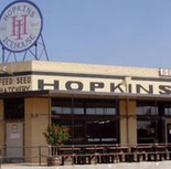 Hopkins Icehouse building with large sign and water tower against a blue sky.