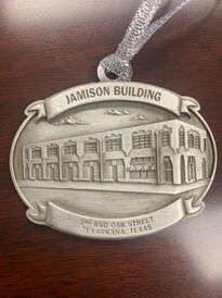 Ornament depicting Jamison Building, Texarkana, TX. Silver oval with building illustration and text.