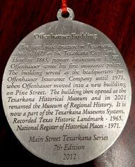 Silver medallion with text about the Offenhauser Building in Texarkana, Texas, listing its history and historical designations.