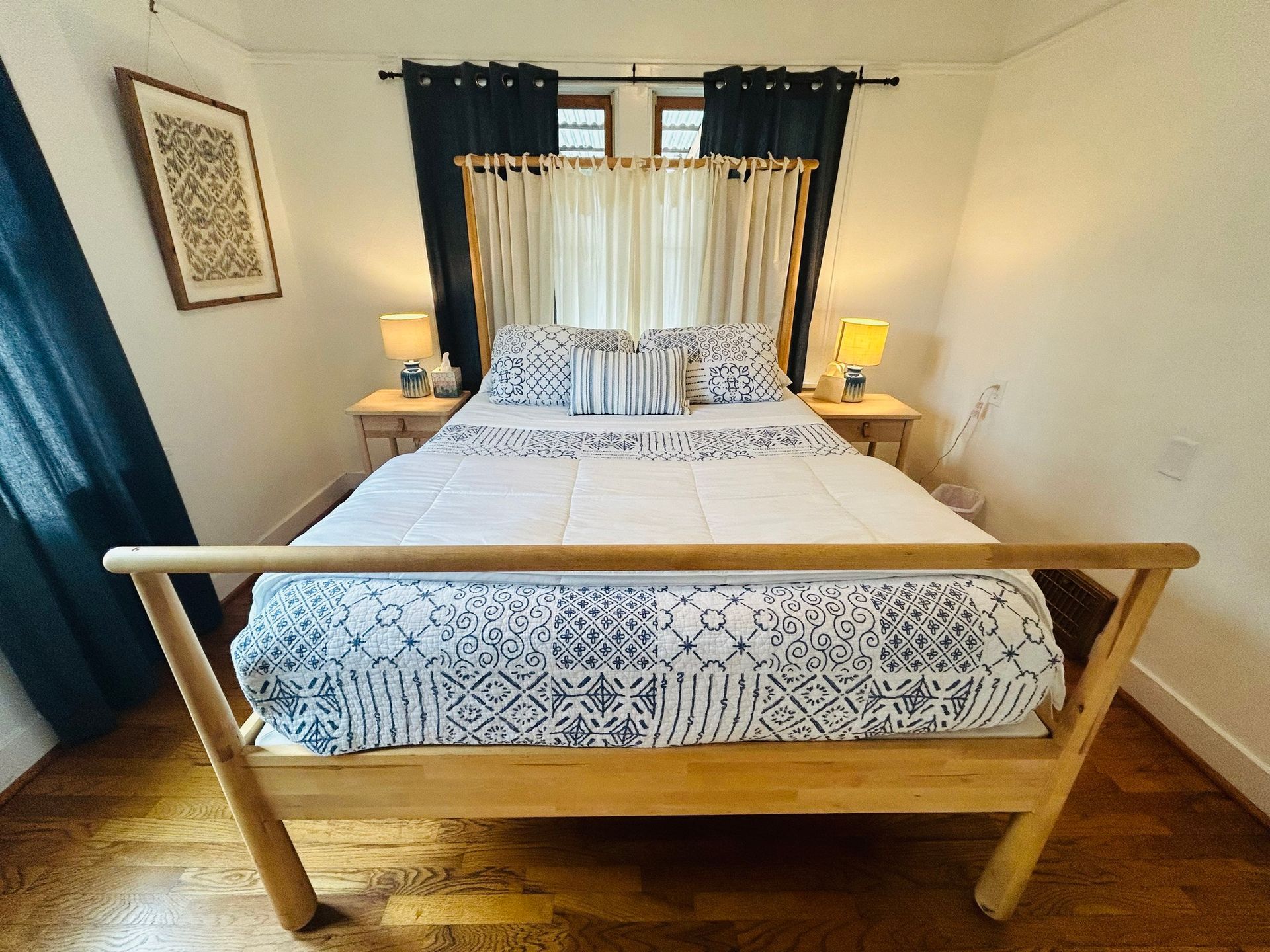A bedroom with a bed , two nightstands and a window.