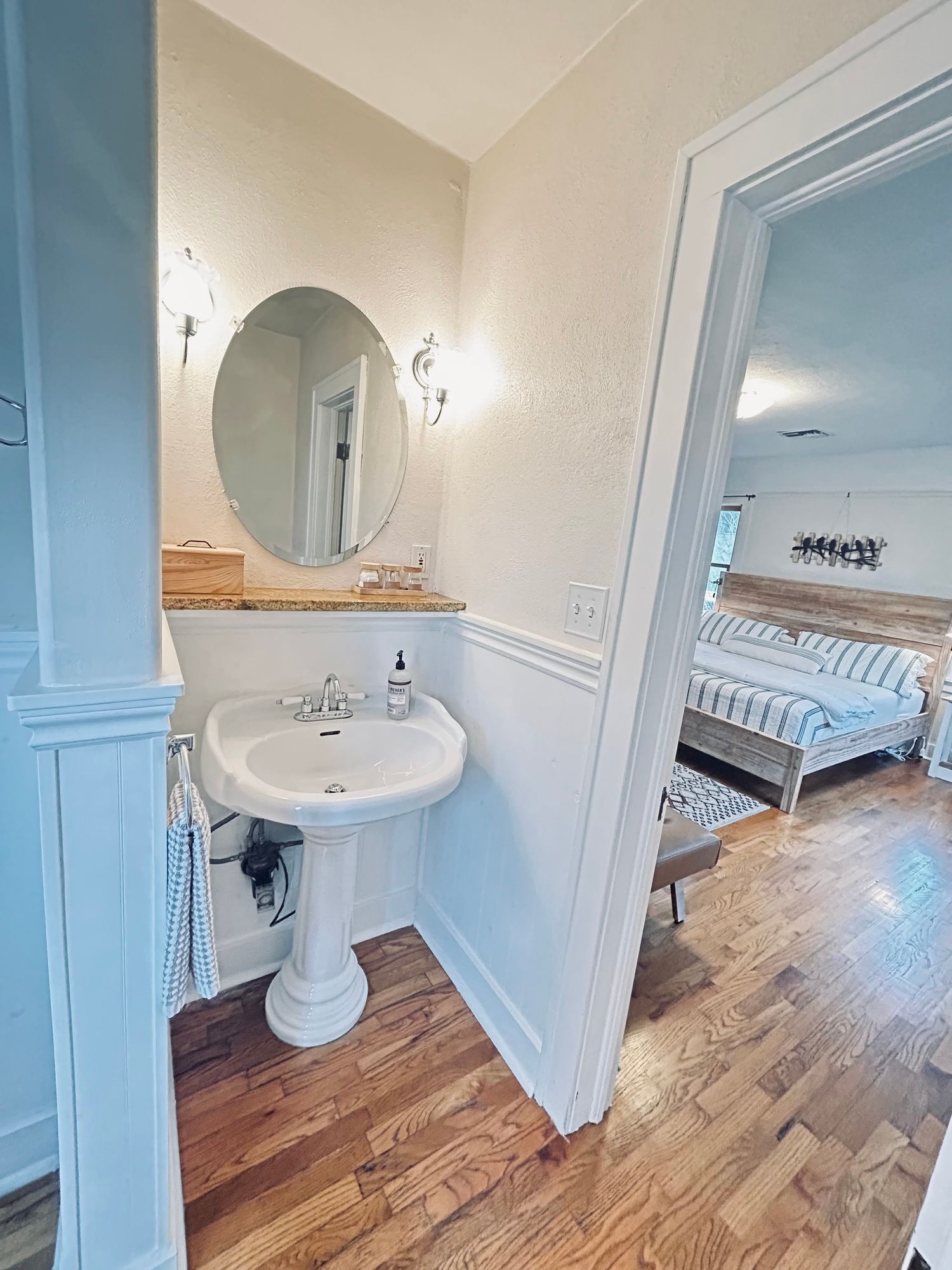 A bathroom with a sink , mirror and hardwood floors.