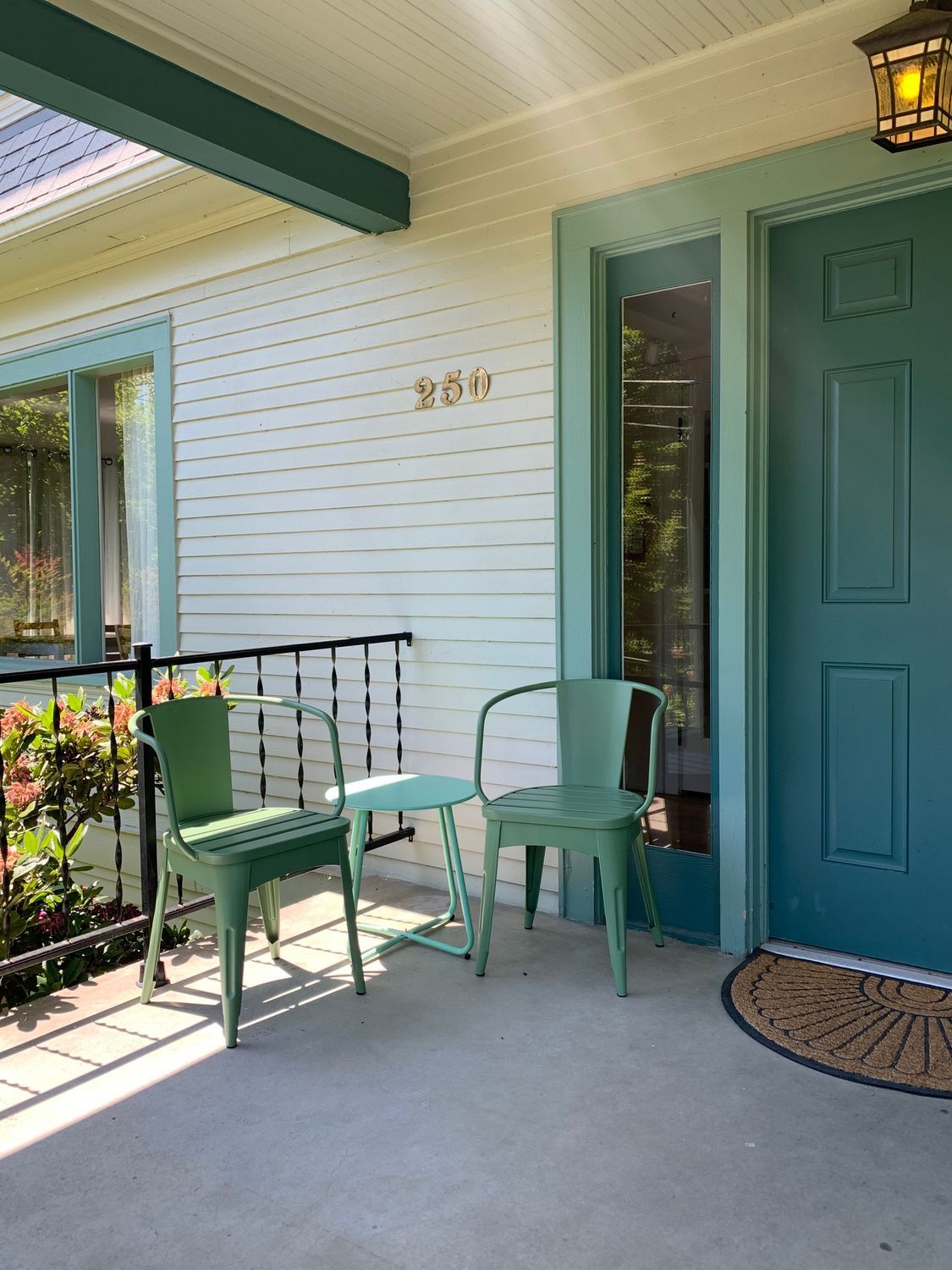 A porch with chairs and a table in front of a blue door.
