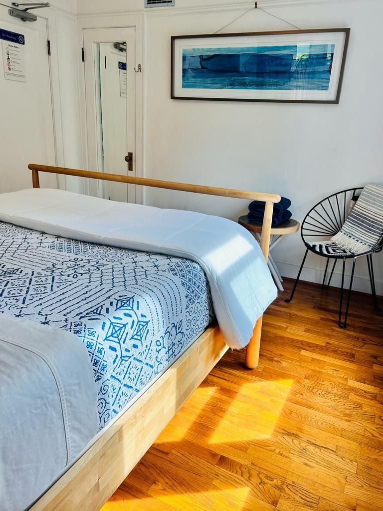 A bedroom with a bed , chair , table and a picture on the wall.