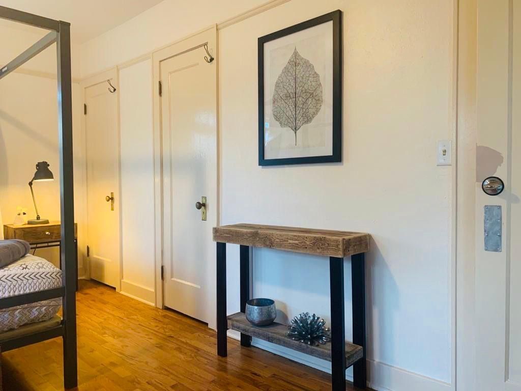 A bedroom with a canopy bed , a table , and a picture on the wall.