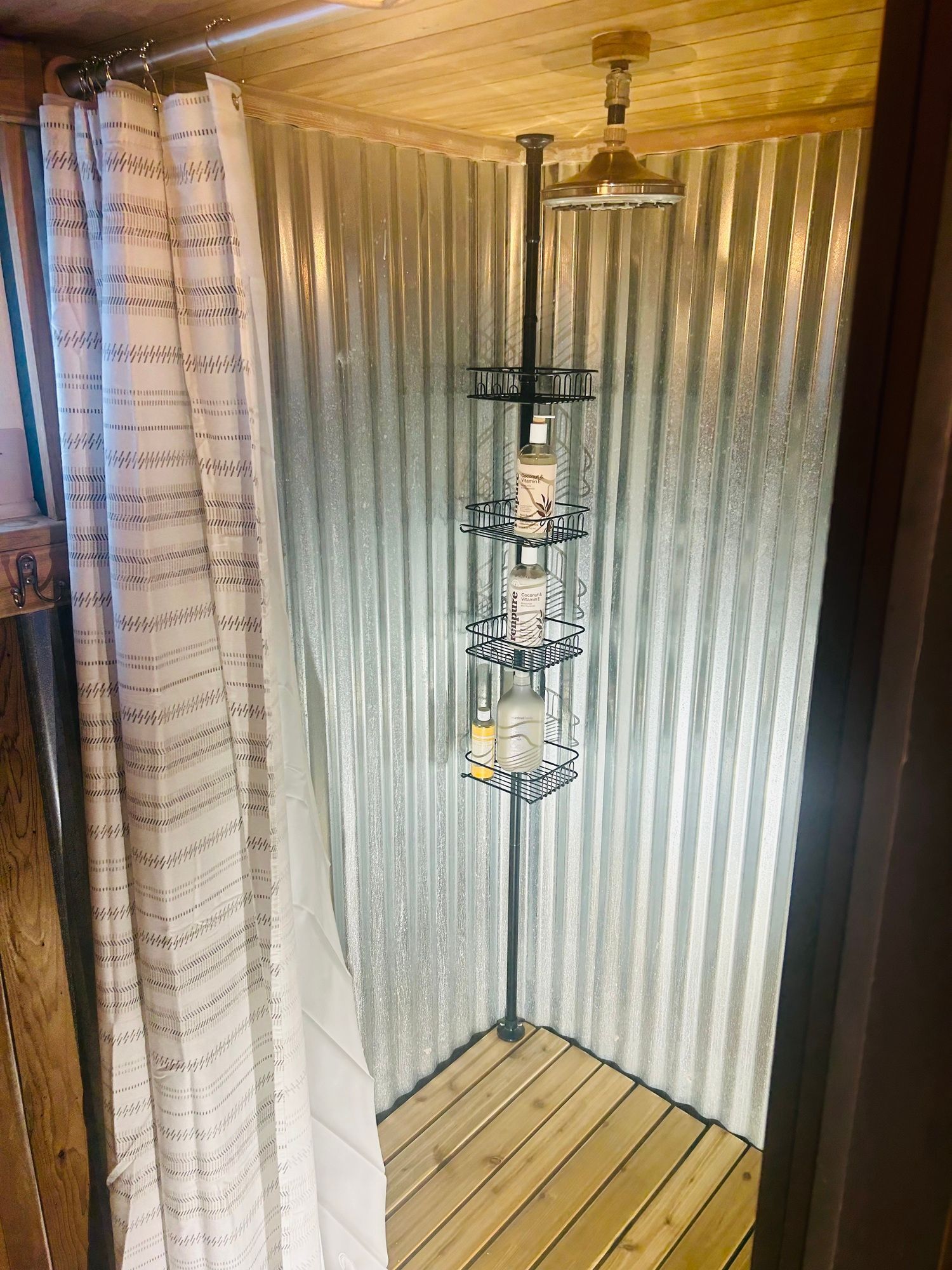 A shower stall with a shower head and a shower curtain.
