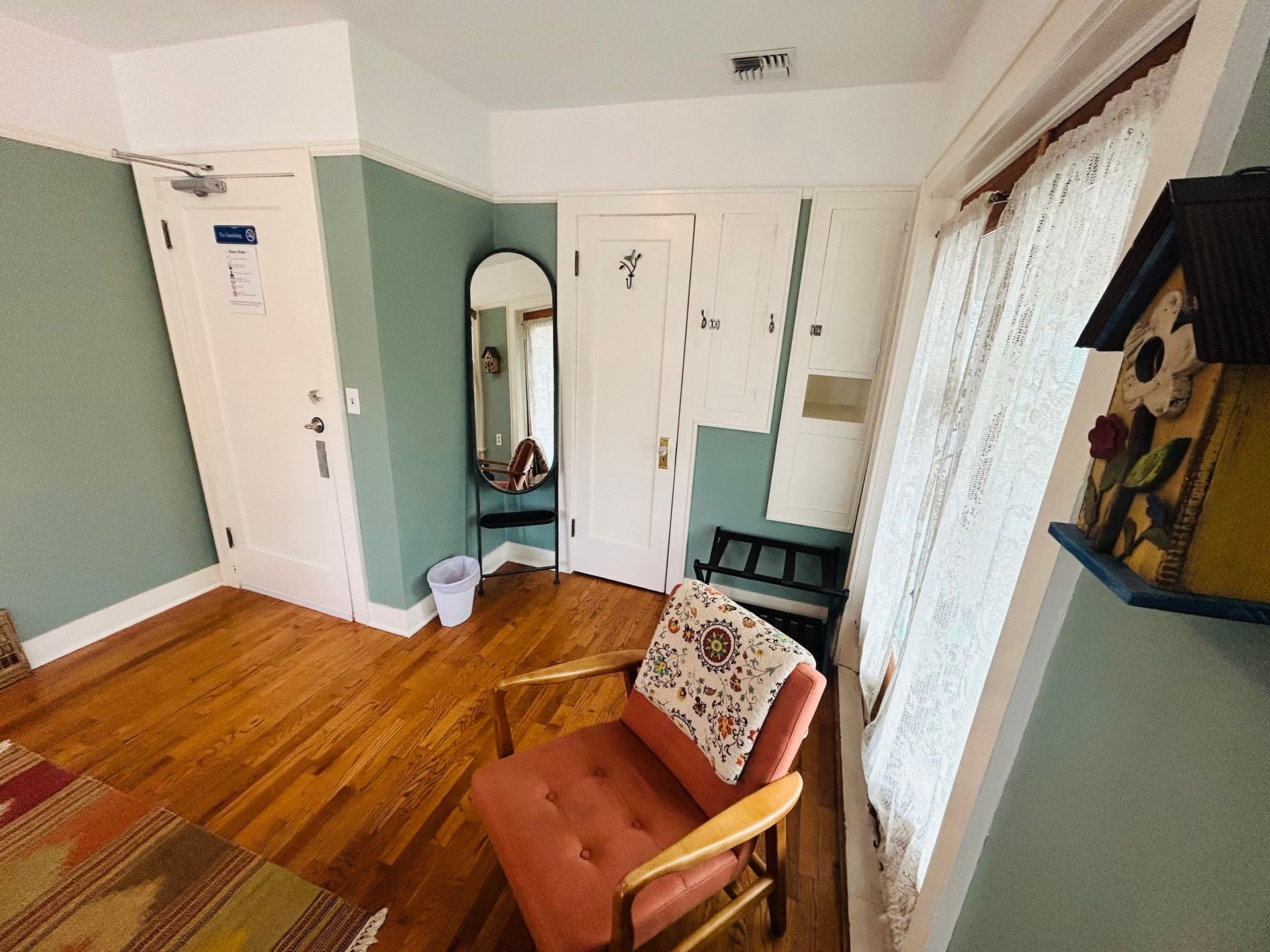 A room with a chair and a birdhouse on the wall