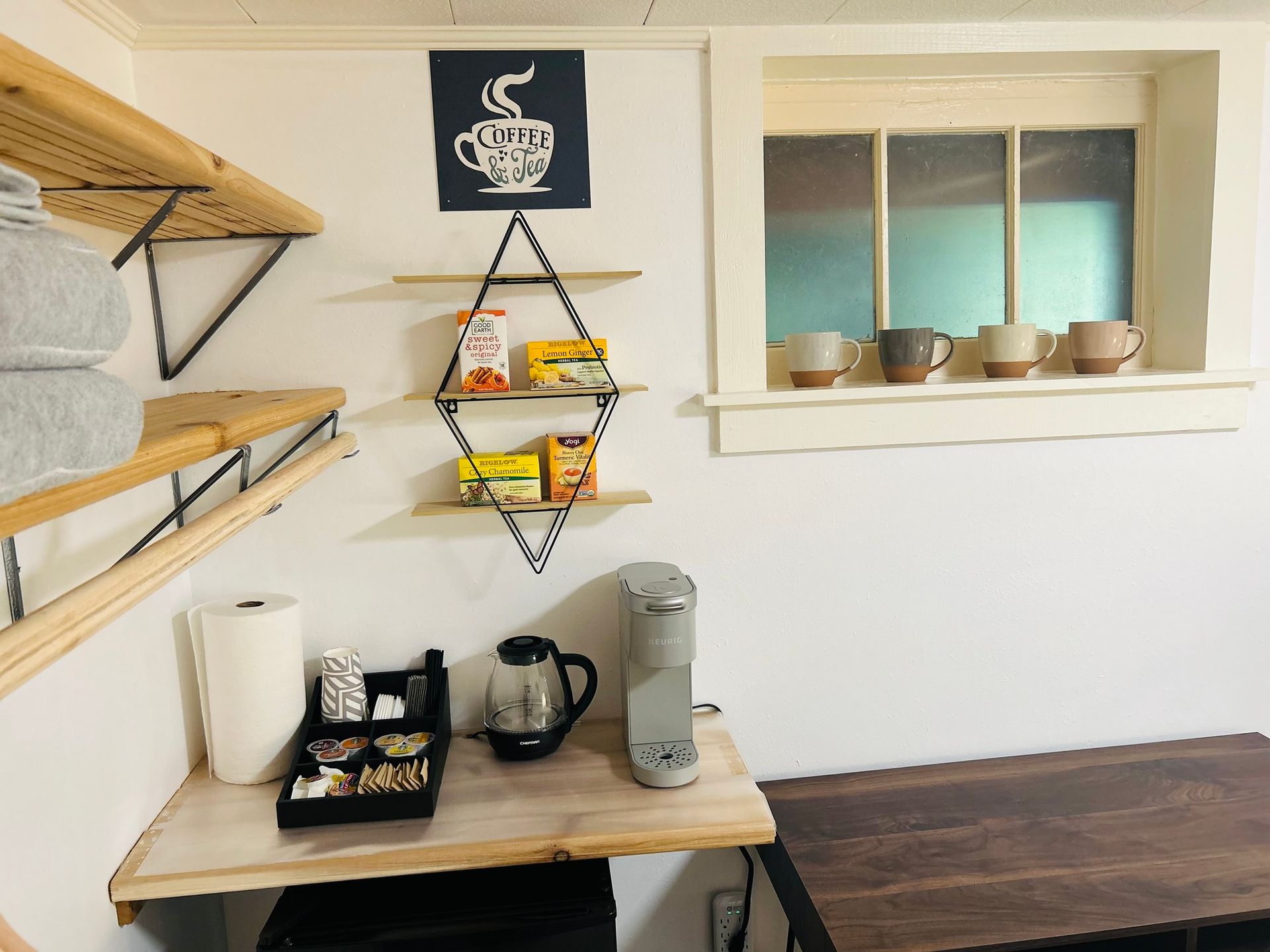 A kitchen with a coffee maker , shelves , and a window.