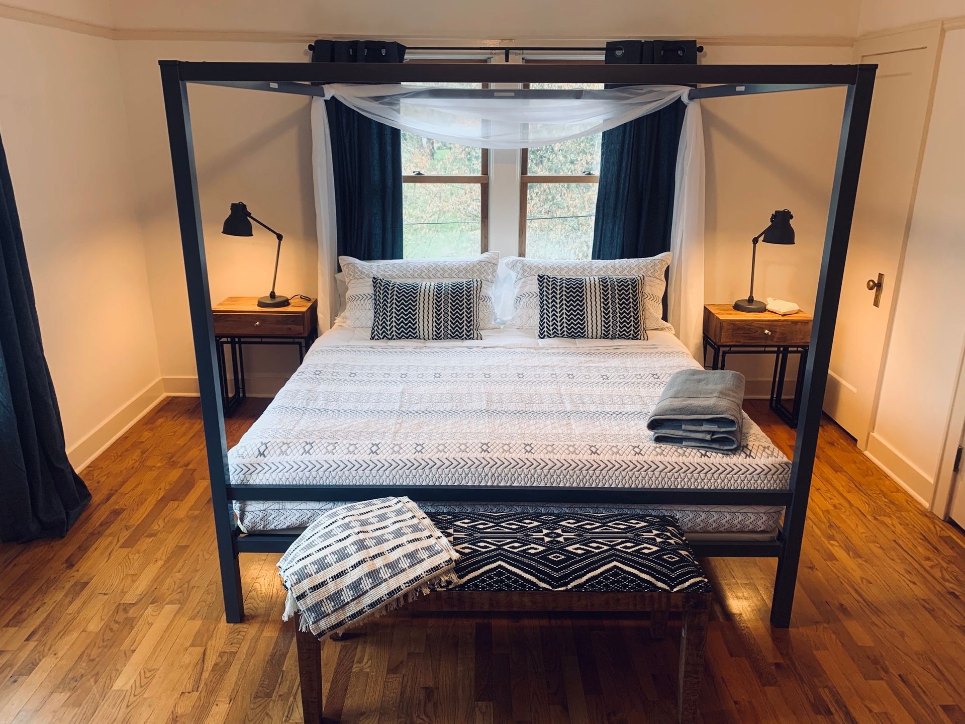 A bedroom with a four poster bed and a bench.