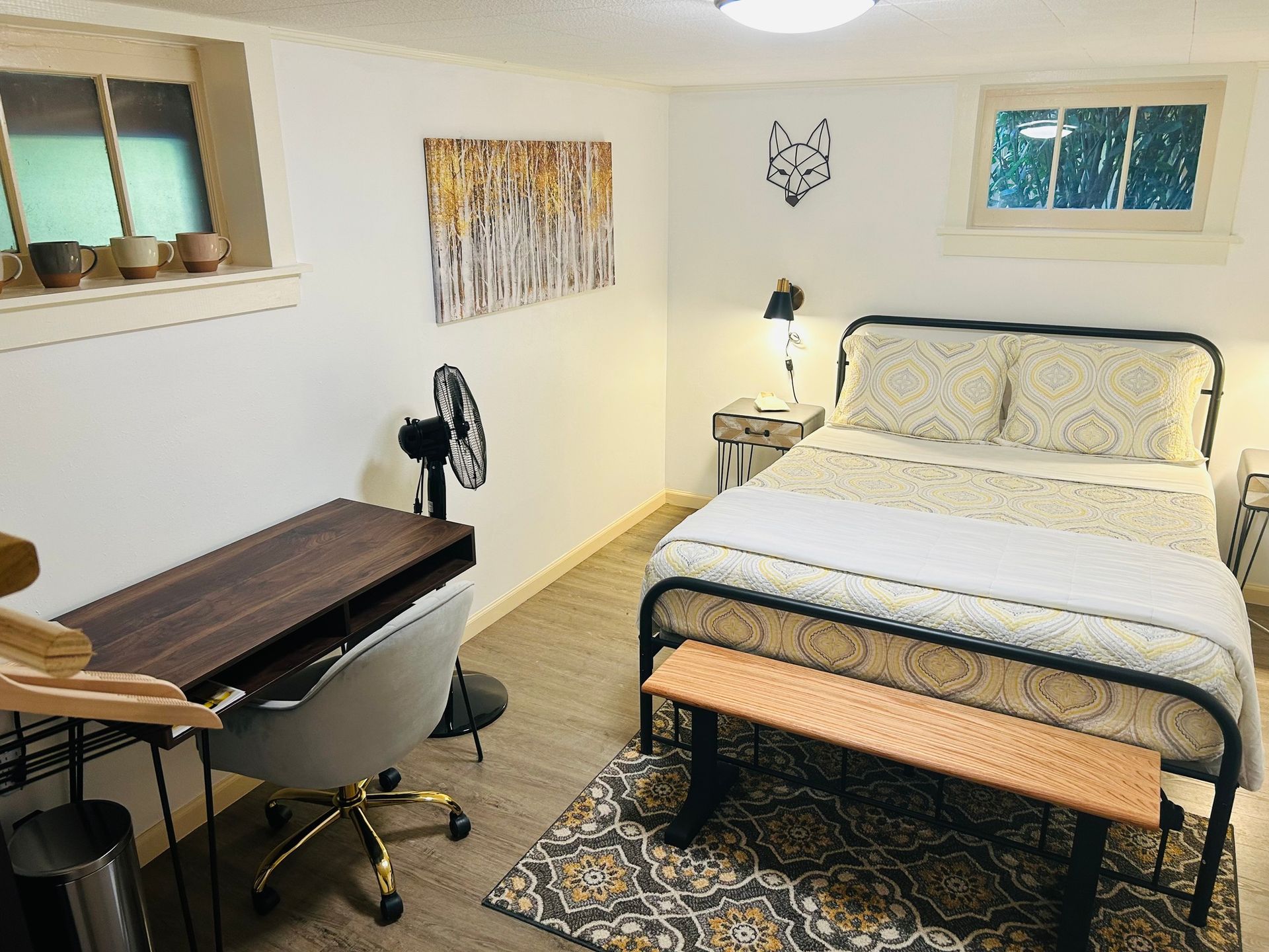 A bedroom with a bed , desk , chair and fan.