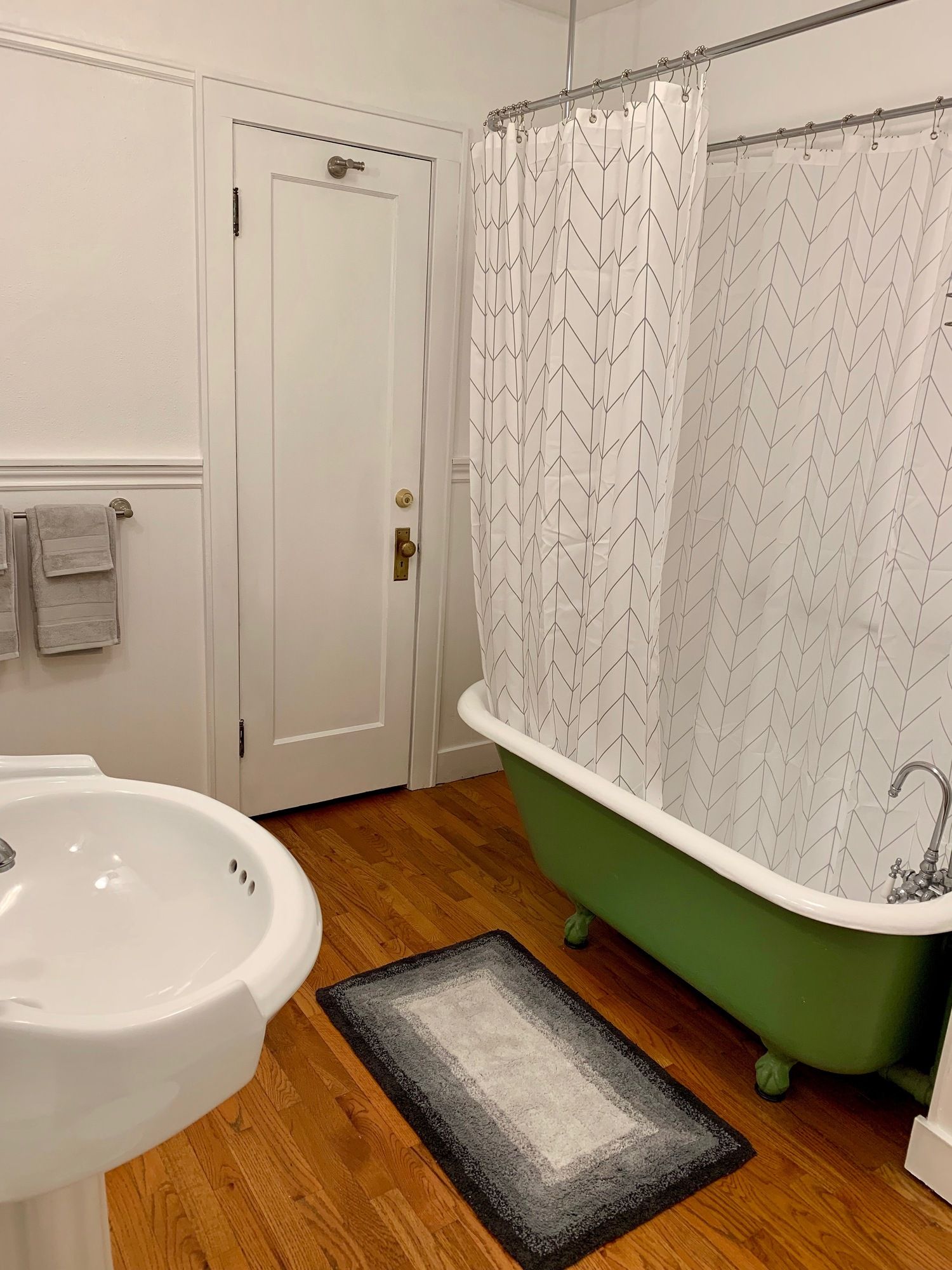 A bathroom with a green tub a sink and a shower curtain