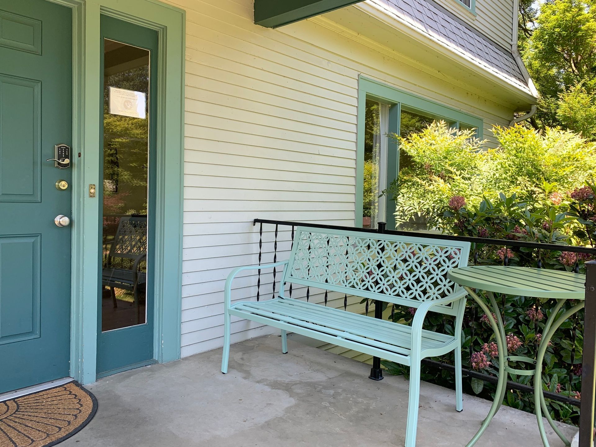There is a bench and a table on the porch of a house.