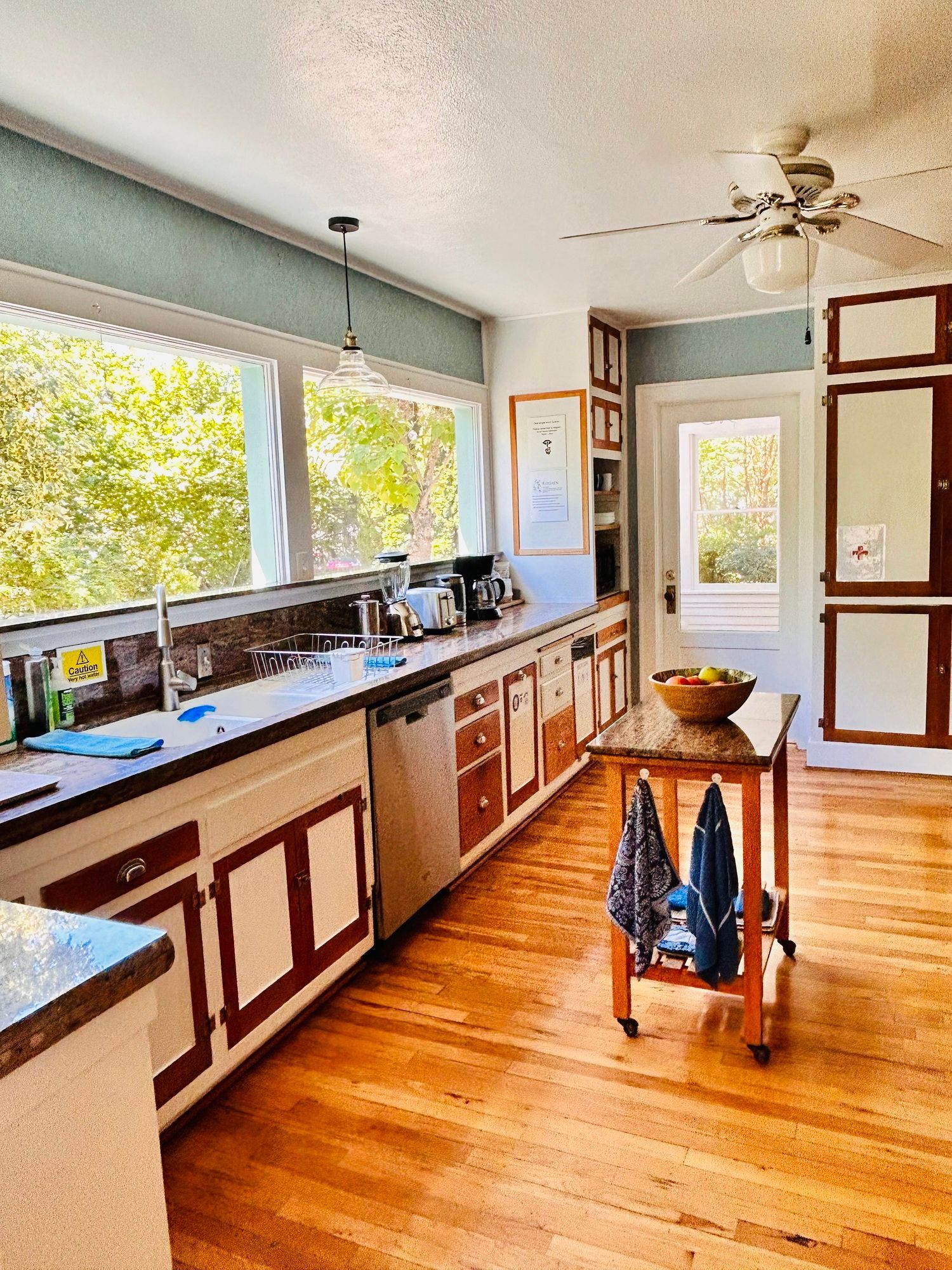 A kitchen with wooden floors and a ceiling fan