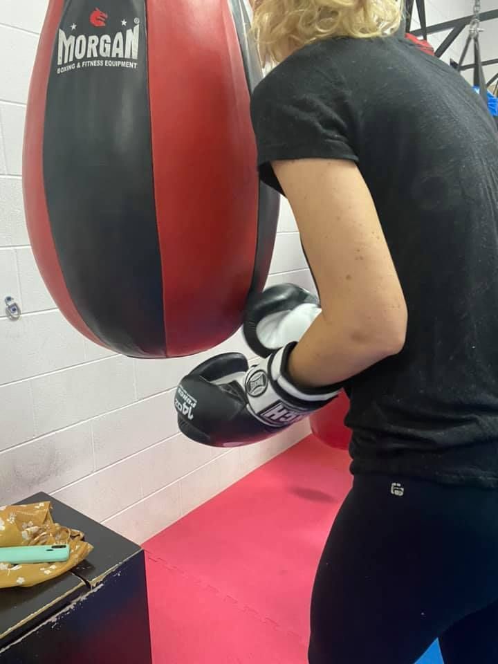 A Girl Trying To Punch The Boxing Bag — Maxenergy Fitness In Smithfield, QLD