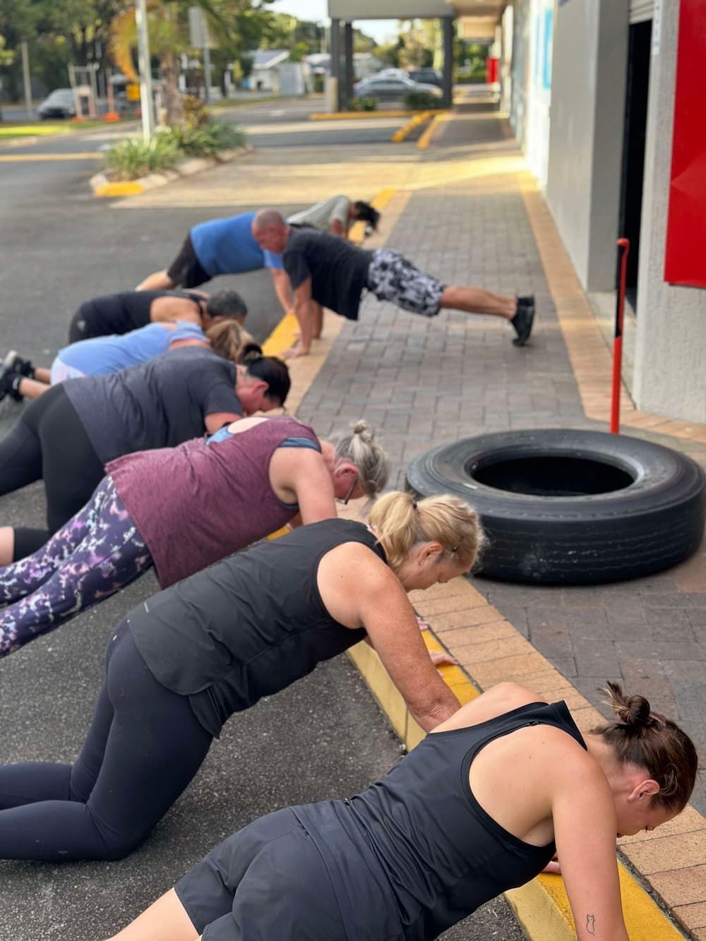 A Group Of People Are Doing Push Ups On The Sidewalk — Maxenergy Fitness In Smithfield, QLD