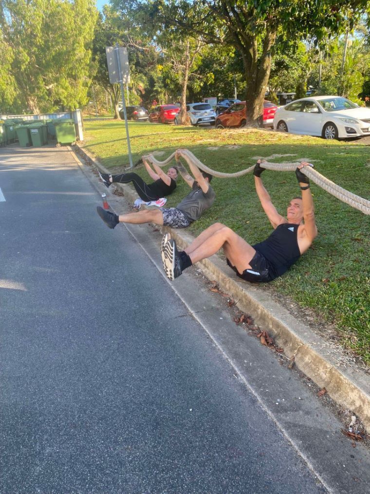 A Group Of People Holding Up A Rope While Sitting On The Sie Of The Road — Maxenergy Fitness in Smithfield, QLD