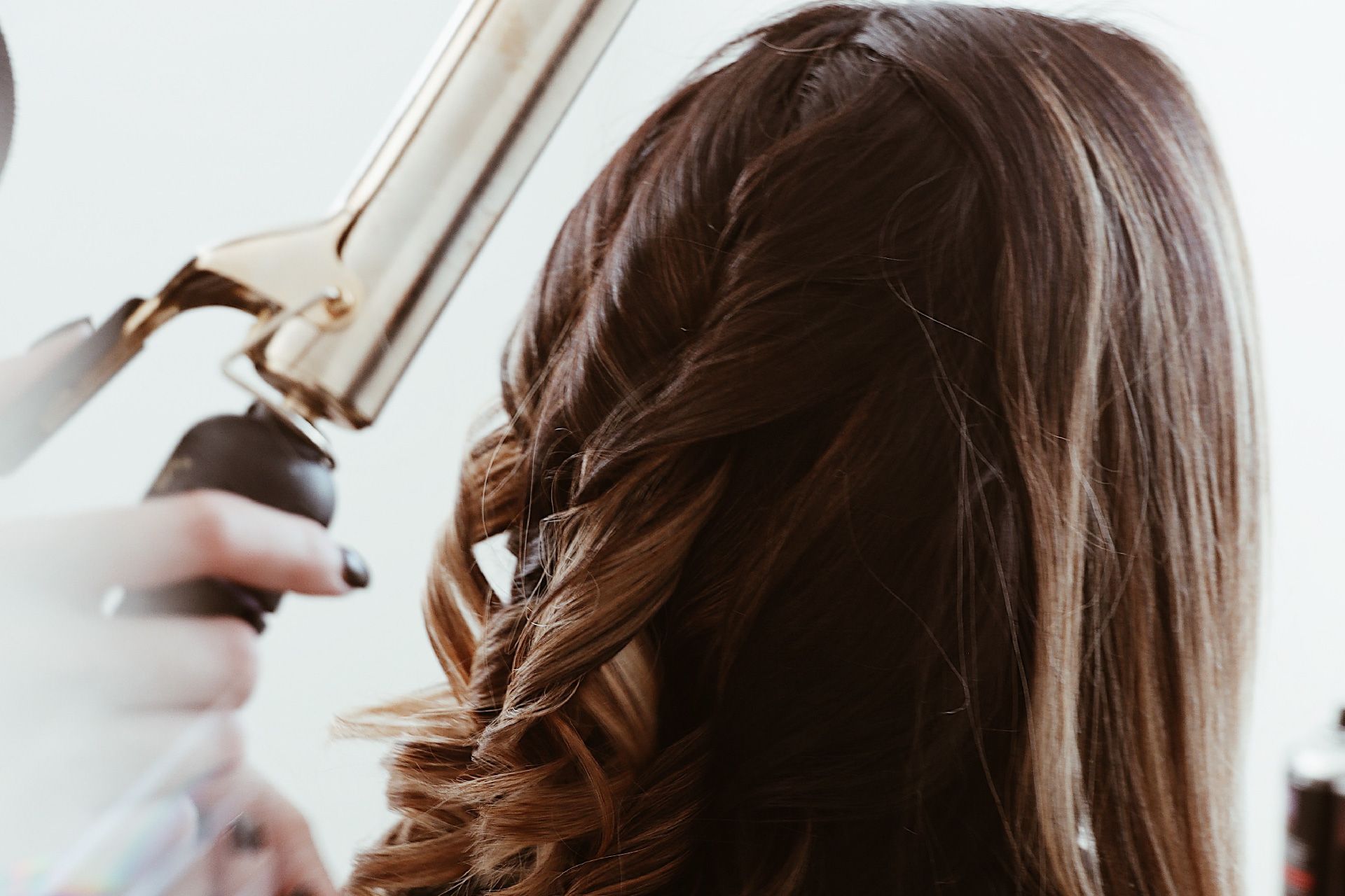 Cabello de mujer peinado con un rizador, creando rizos sueltos.