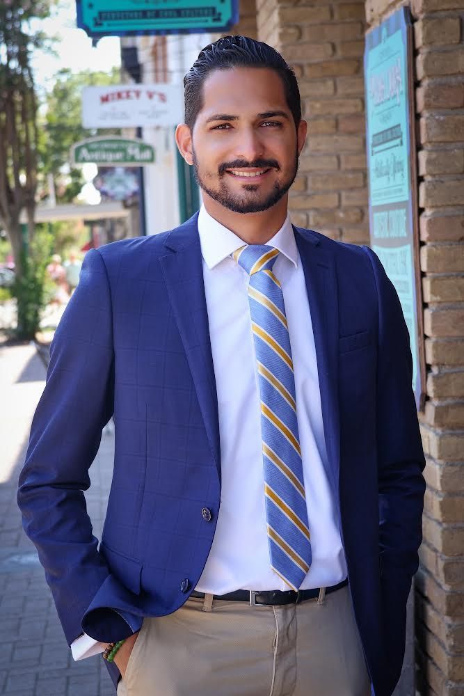 A man in a suit and tie is standing in front of a brick building.