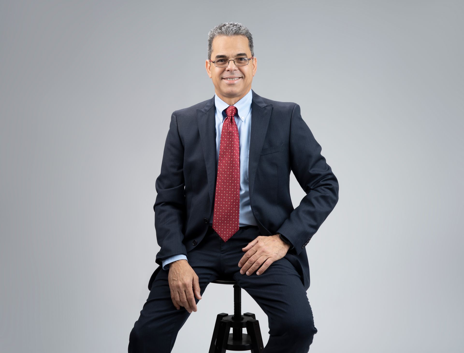 A man in a suit and tie is sitting on a stool.