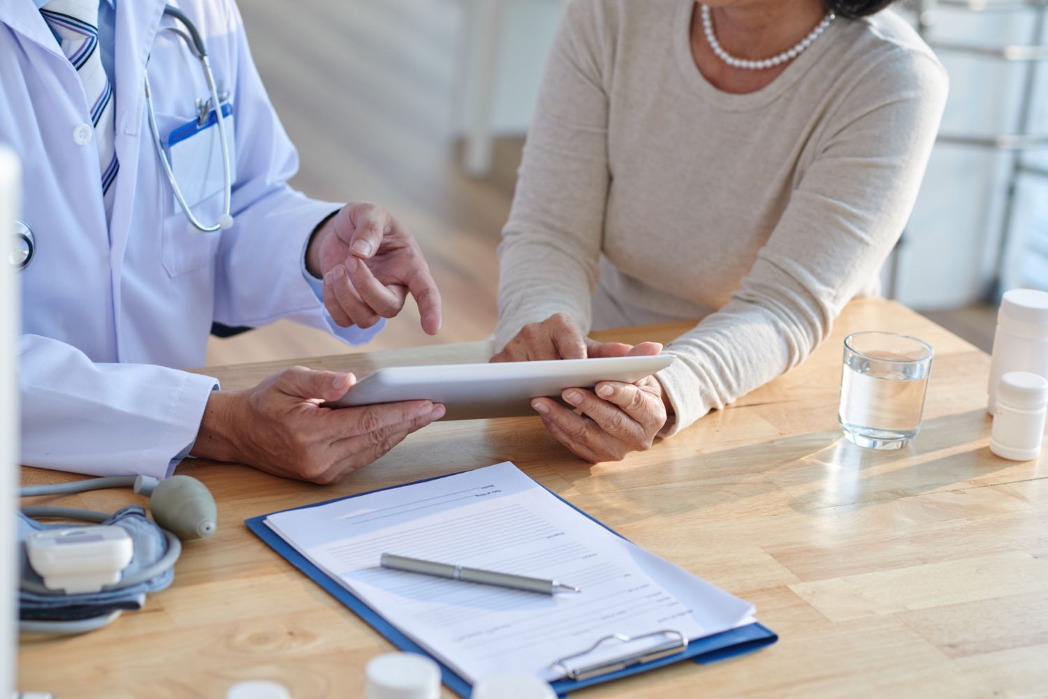 Doctor and patient reviewing medical information on a tablet at a desk.