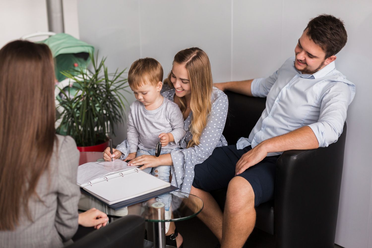 A family with a young child signing paperwork with a professional in an office setting.