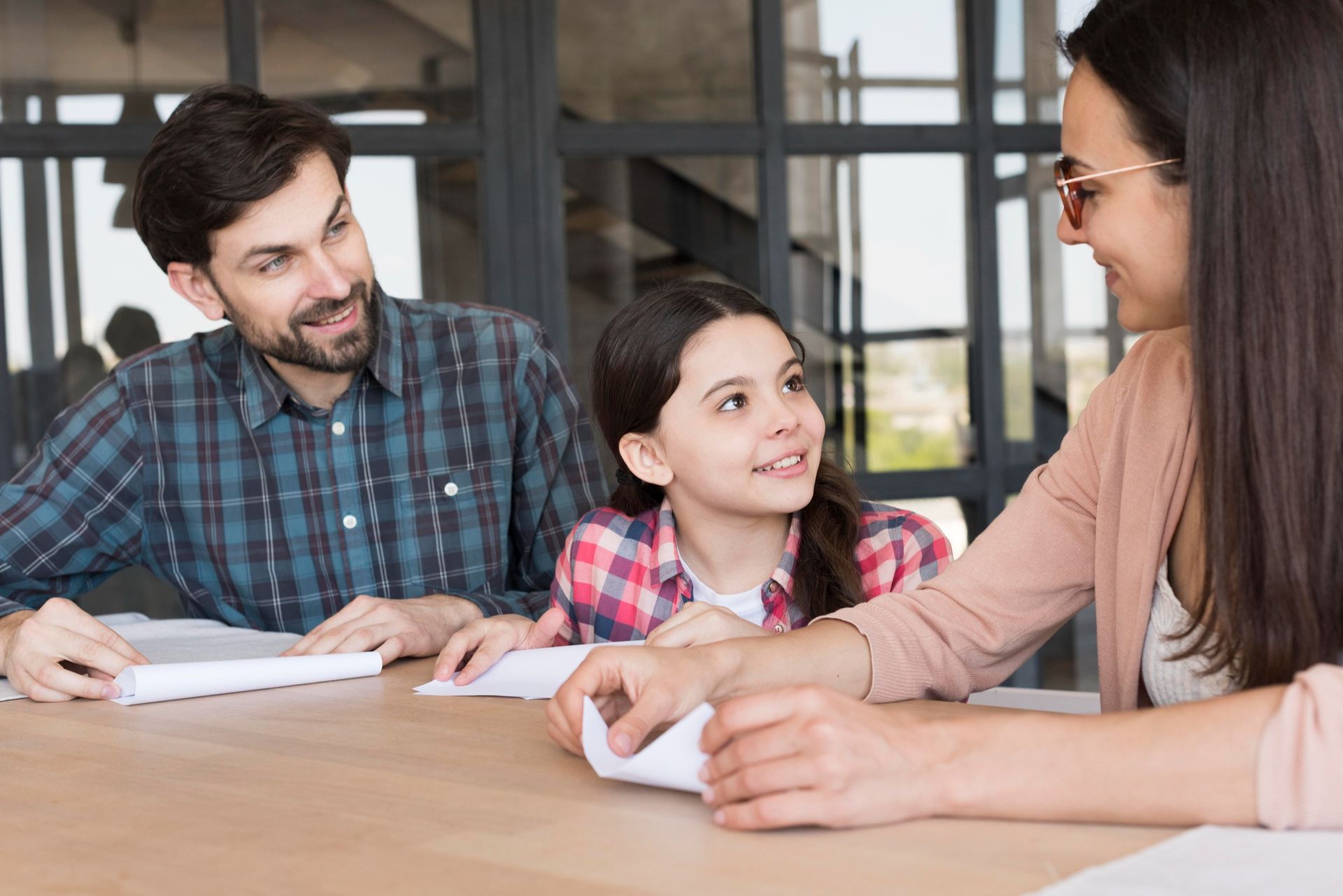 Family at table smiling, looking at each other, papers present.