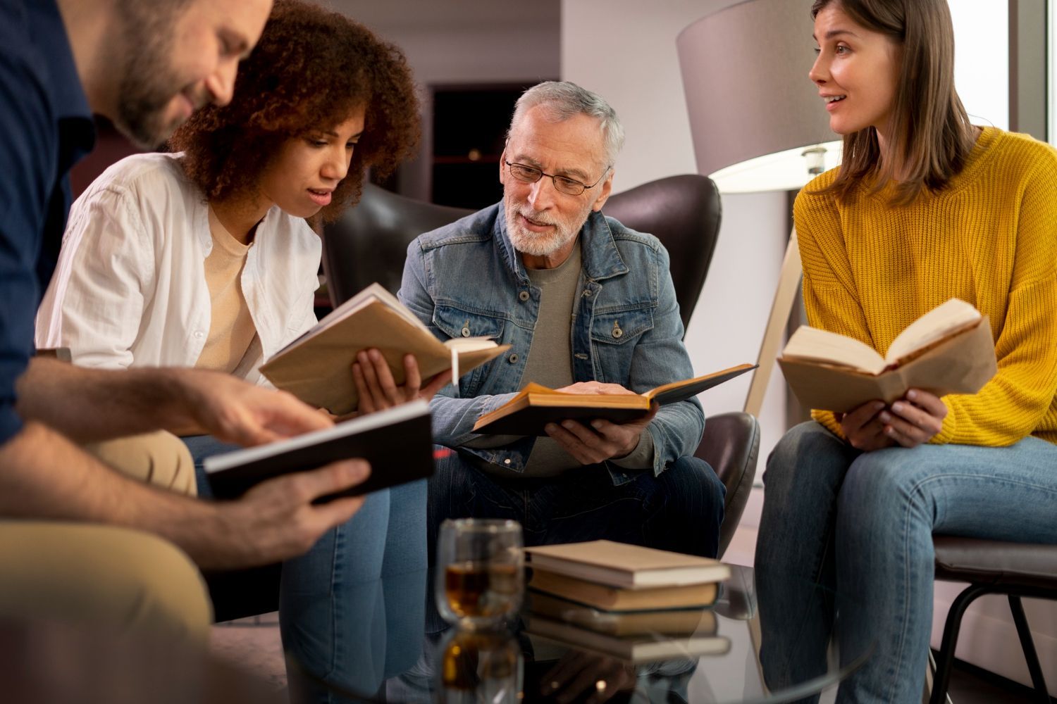 Four people in a living room read books, engaging in a group discussion.