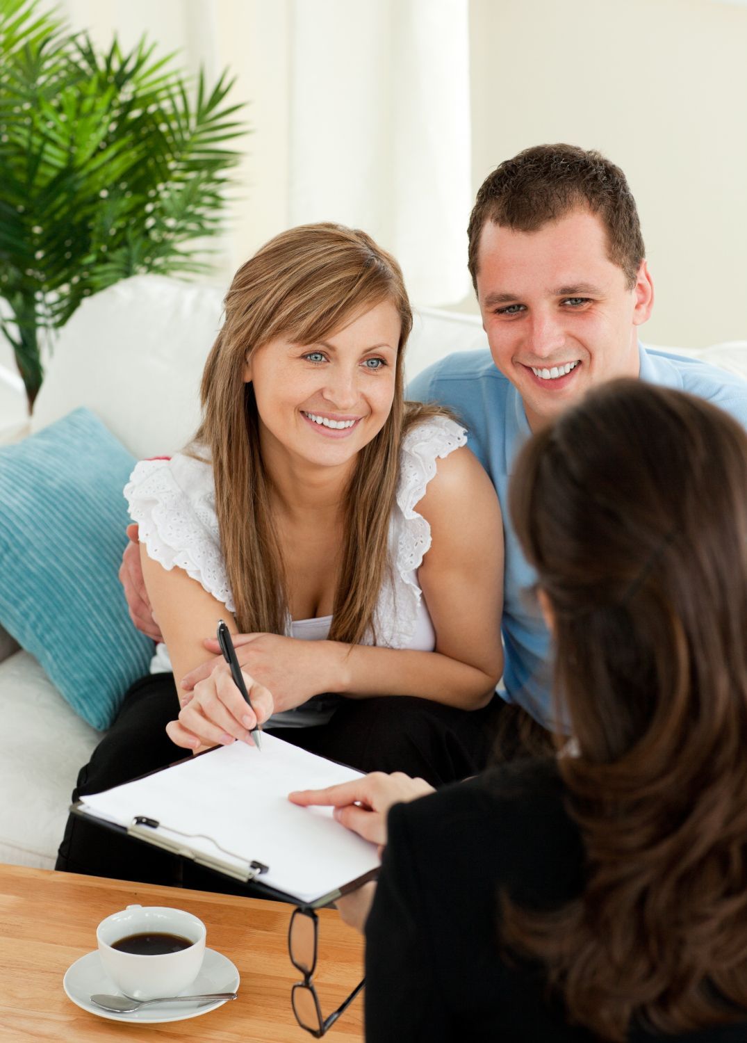 Couple consults with a professional; they smile while reviewing paperwork in a home setting.