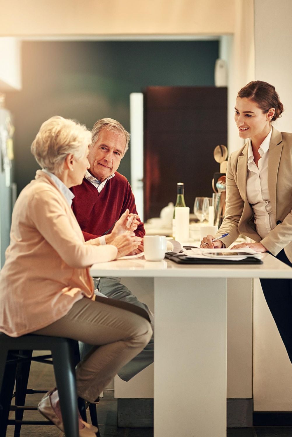 Senior couple meeting with a financial advisor at a kitchen counter.