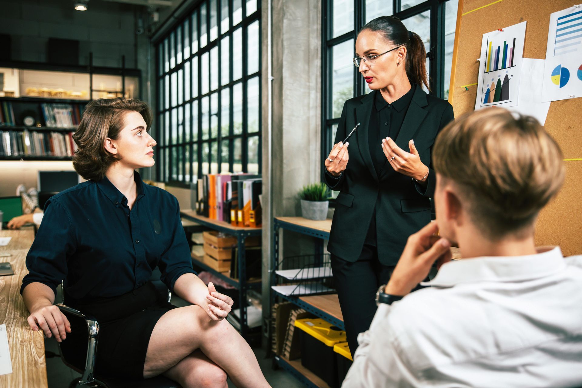 Business meeting with three people, two women and one man, in an office setting.